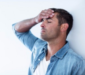 Anxious man against wall with hand on forehead: CannaClix CBD Oils Blog